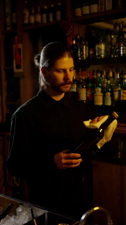 Bartender Inspecting Bottle in Cozy Bar Setting Stock Footage 262661973