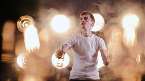 Bartender juggling bottles on the light background with smoke on it. Barman show Stock Footage 164873985