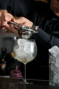The bartender makes a cocktail at the bar. Macro shooting with drops and hand Stock Photos