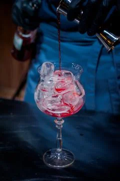 The bartender makes a red cocktail. Blue dark background Stock Photos