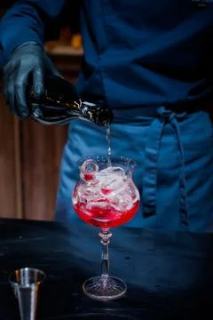 The bartender makes a red cocktail. Blue dark background Stock Photos