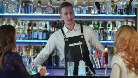 Bartender is making cocktail at bar counter for two girl Vidéo 76636007