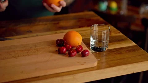 A Bartender Making a Cocktail with Orange and Cherries Stock Footage 244360788