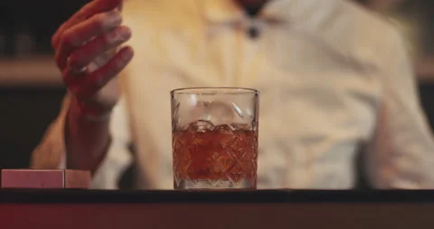 Bartender making a cocktail in speakeasy bar with orange peel garnish Stock Footage 144442345