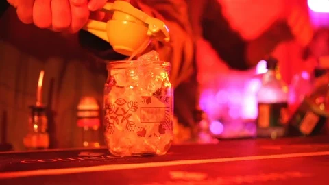 The bartender making a cocktail squeezes the juice of citrus into a glass Stock Footage 123217209