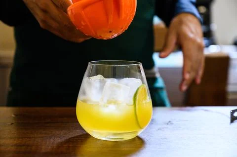 Bartender making cocktail squeezing citrus juice into glass Stock Photos
