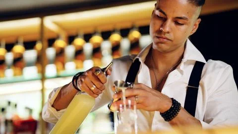 Bartender making cocktail using jigger at illuminated bar Stock Photos