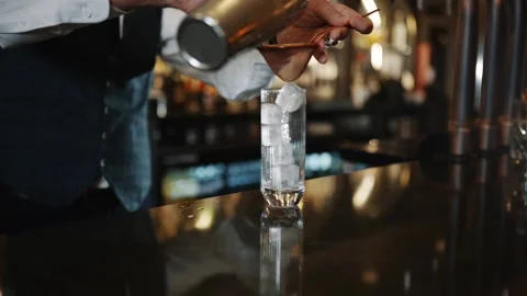 A bartender is making a drink with ice cubes in a glass Stock Footage 295996054