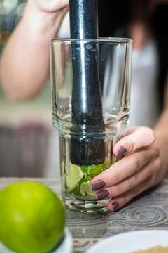 Bartender making refreshing coctail on a bar background. Dark moody style. Ic Stock Photos