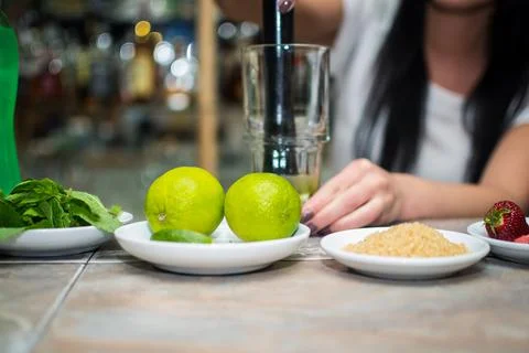Bartender making refreshing coctail on a bar background. Dark moody style. Ic Stock Photos