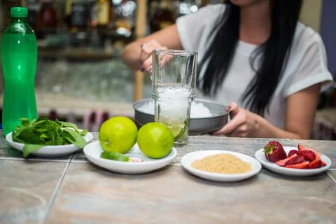 Bartender making refreshing coctail on a bar background. Dark moody style. Ic Stock Photos