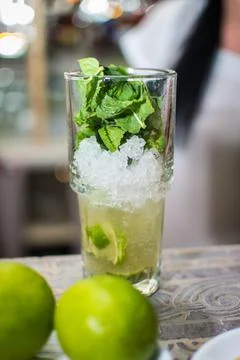 Bartender making refreshing coctail on a bar background. Dark moody style. Ic Stock Photos