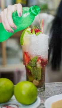 Bartender making refreshing coctail on a bar background. Dark moody style. Ic Stock Photos