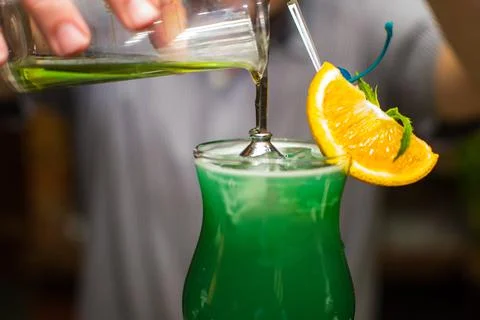 Bartender making refreshing coctail on a bar background. Dark moody style. Ic Stock Photos