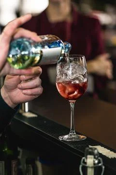 Bartender making refreshing pink coctail with a rose on top isolated on a bar Stock Photos