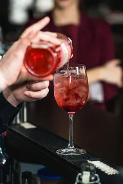 Bartender making refreshing pink coctail with a rose on top isolated on a bar Stock Photos