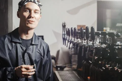 Bartender man stands next to beer faucets. Stock Photos