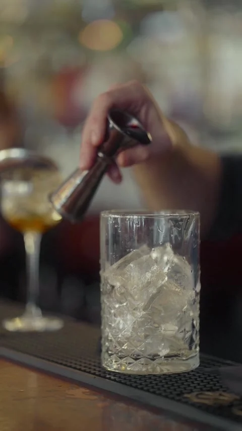 Bartender measures the cocktail ingredients from a jigger into a glass with ice. Stock Footage 271662004