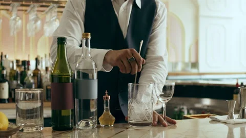 Bartender mixologist combining ingredients and making a Martini cocktail in a be Stock Footage 199456750