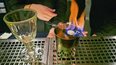 Bartender performs a fiery cocktail technique at a stainless bar station, with Stock Footage 339849126