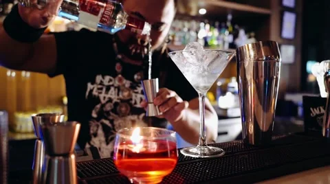 Bartender with piercings and dreadlocks making cocktail: pouring vodka Stock Footage 65397619