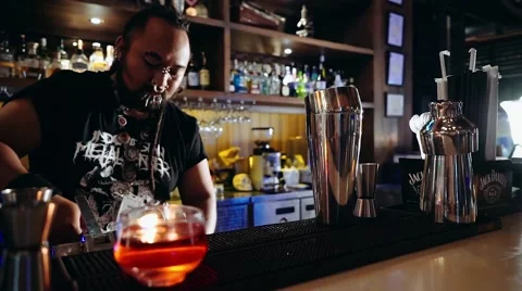 Bartender with piercings and dreadlocks putting ice into glass Stock Footage 65398099