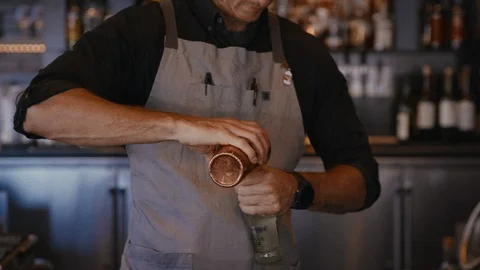 Bartender pops cap off of bottle with cocktail shaker Stockbeeldmateriaal 99598402