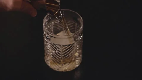 Bartender Poured Whisky On The Jigger Into The Old Fashioned Glass With Ice Stock Footage 332945049