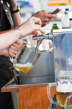 Bartender pouring beer into a glass from a machine, close-up Stock Photos