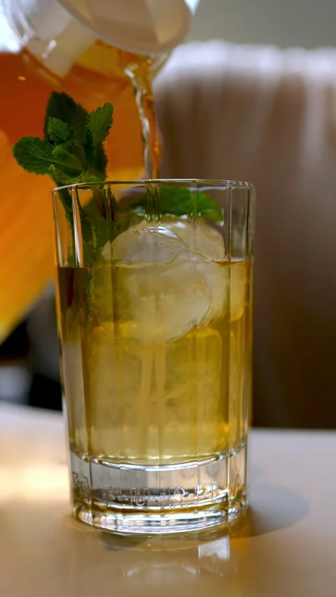 Bartender pouring chilled tea into ice filled glass, garnishing with fresh mint Stock Footage 309147936