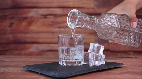 Bartender pouring clear liquor such as vodka or tequila from fancy bottle Stock Footage 247923294
