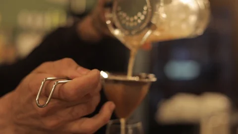 Bartender Pouring Cocktail in Glass Using Cocktail Strainer Stock Footage 129780405