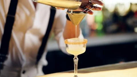 Bartender pouring cocktail using strainer preparing drink Stock Photos