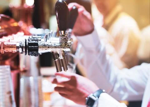 Bartender pouring draft beer in the bar, Barman hand at beer tap pouring drau Stock Photos