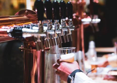 Bartender pouring draft beer in the bar, Barman hand at beer tap pouring drau Stock Photos