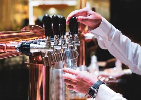Bartender pouring draft beer in the bar, Barman hand at beer tap pouring drau Stock Photos