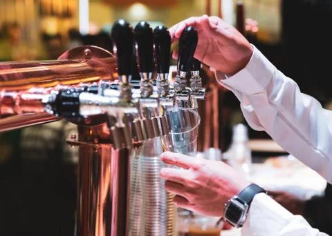 Bartender pouring draft beer in the bar, Barman hand at beer tap pouring drau Stock Photos