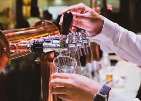 Bartender pouring draft beer in the bar, Barman hand at beer tap pouring drau Stock Photos