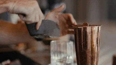 Bartender pouring drink through strainer into glass Stockbeeldmateriaal 99599690