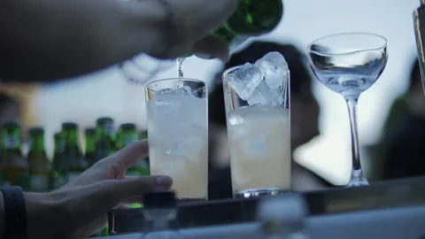 Bartender pouring drinks into tall glasses with ice Stock Footage 312748043