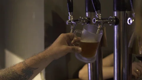 Bartender pouring fresh beer in mug from beer tap in irish pub. Brewer pouring Stock Footage 104531282