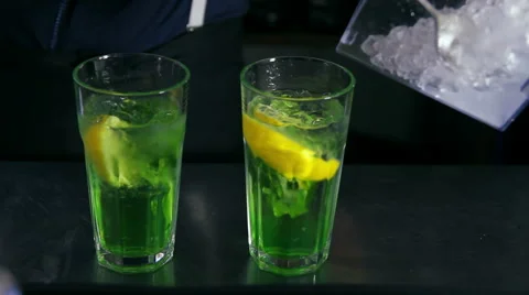 Bartender pouring ice and decorating two cocktails with mint Stock Footage 41779616