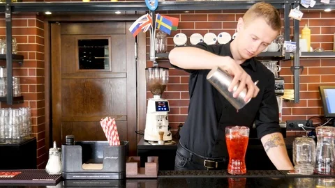 Bartender pouring liquid into prepared glass through cocktail strainer Stock Footage 116557518