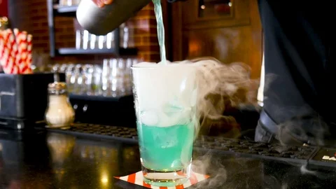 Bartender pouring liquid from shaker to a cocktail glass with cold smoke Stock Footage 116329790