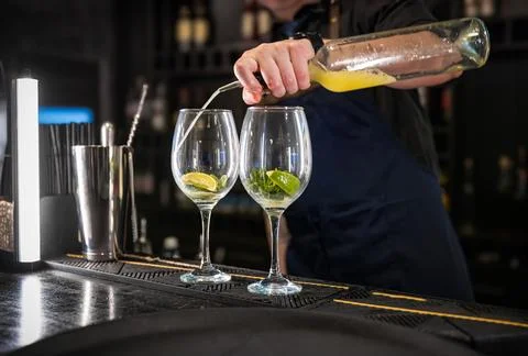 Bartender pouring a mixed drink into two elegant glasses Stock Photos