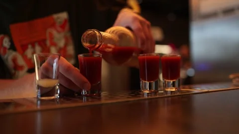 Bartender pouring red shots into glasses at bar Stock Footage 315598275