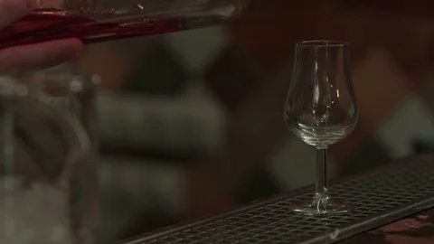 Bartender pouring red wine into a tall glass in a bar Vídeos de archivo 73687758