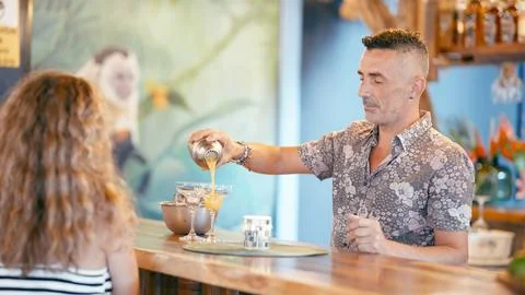 Bartender pouring refreshing cocktail for customer at tropical bar Stock Photos