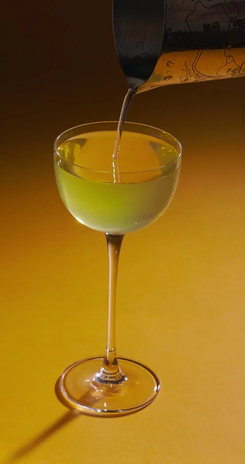 Bartender pouring refreshing cocktail from shaker on yellow background. Summer Stock Footage 308417499