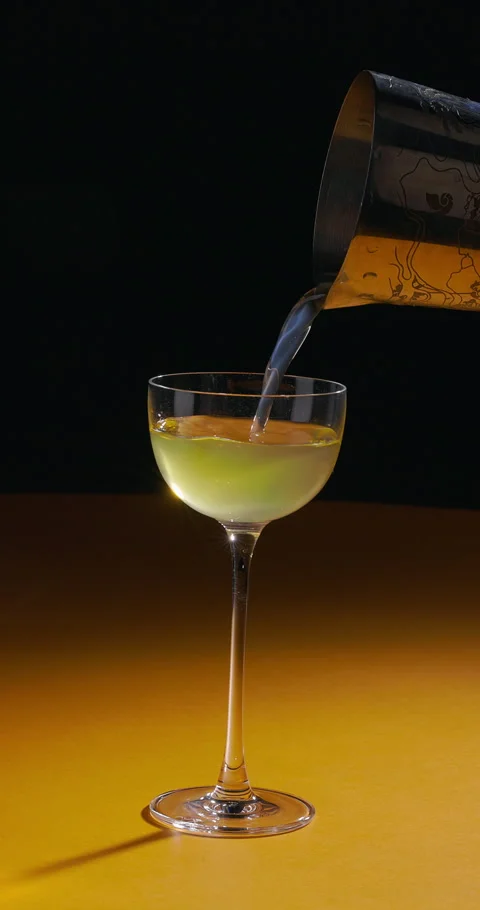 Bartender pouring refreshing cocktail from shaker on yellow black background Stock Footage 312355388